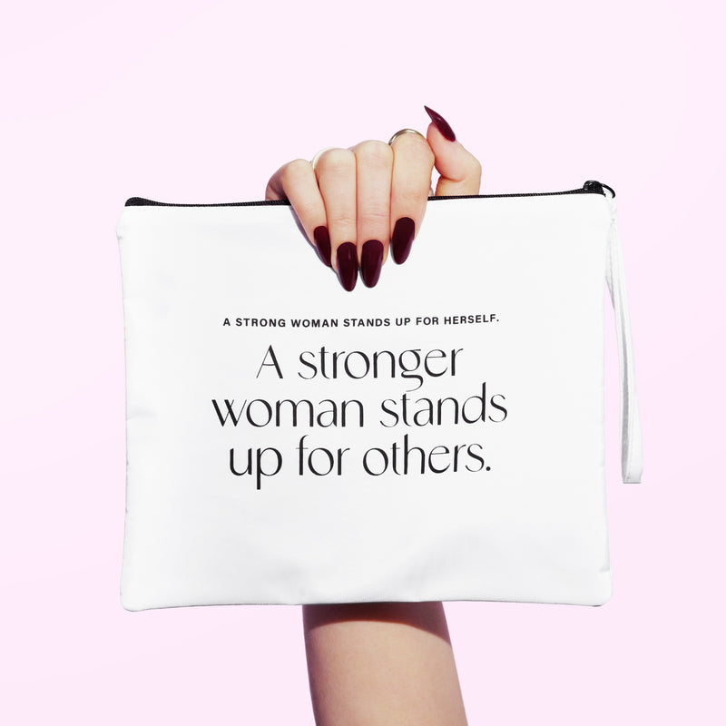 A hand holding a white bag that says "A strong woman stands up for herself. A stronger woman stands up for others."