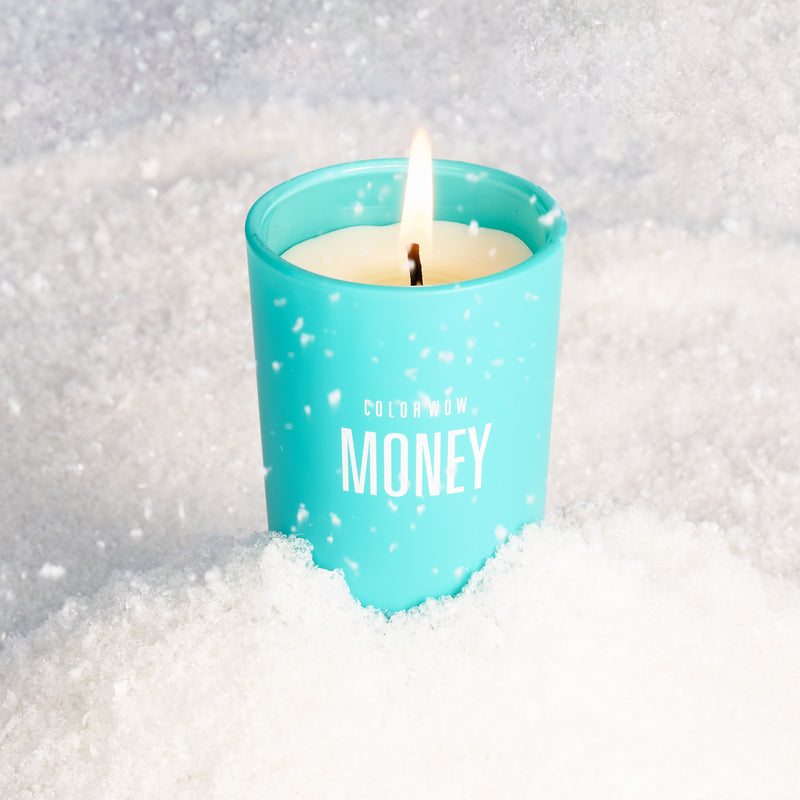 Color Wow money candle lit in the snow