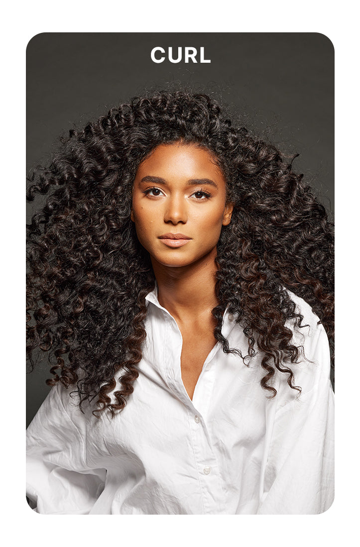 Model with long, voluminous, defined curls wearing a white button-up shirt against a dark gray background. Bold white text above reads: “CURL.”
