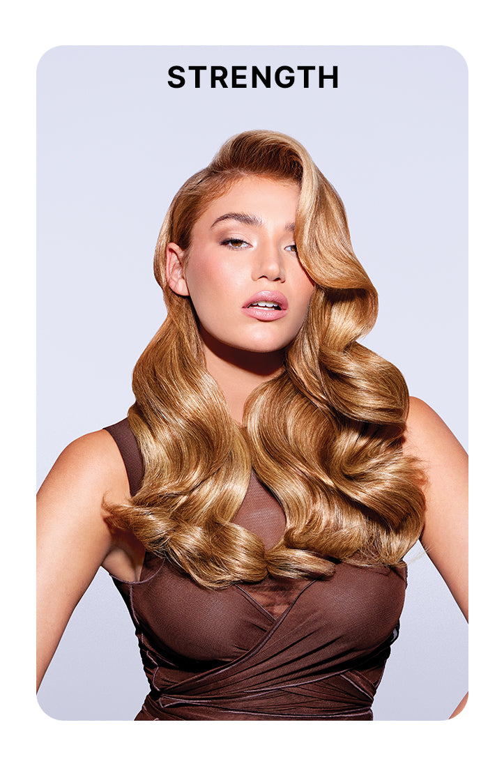 Model with voluminous, glossy, golden blonde waves styled in a deep side part, wearing a sleeveless brown top against a pale lavender background. Bold black text above reads: “STRENGTH.”